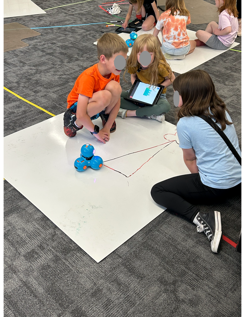 Group of three students sitting in a circle on the floor using math manipulatives